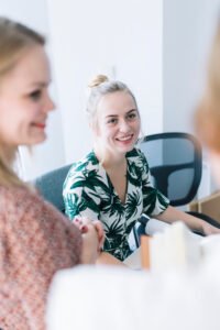 Group of happy women waiting in an office, smiling and engaging with each other.