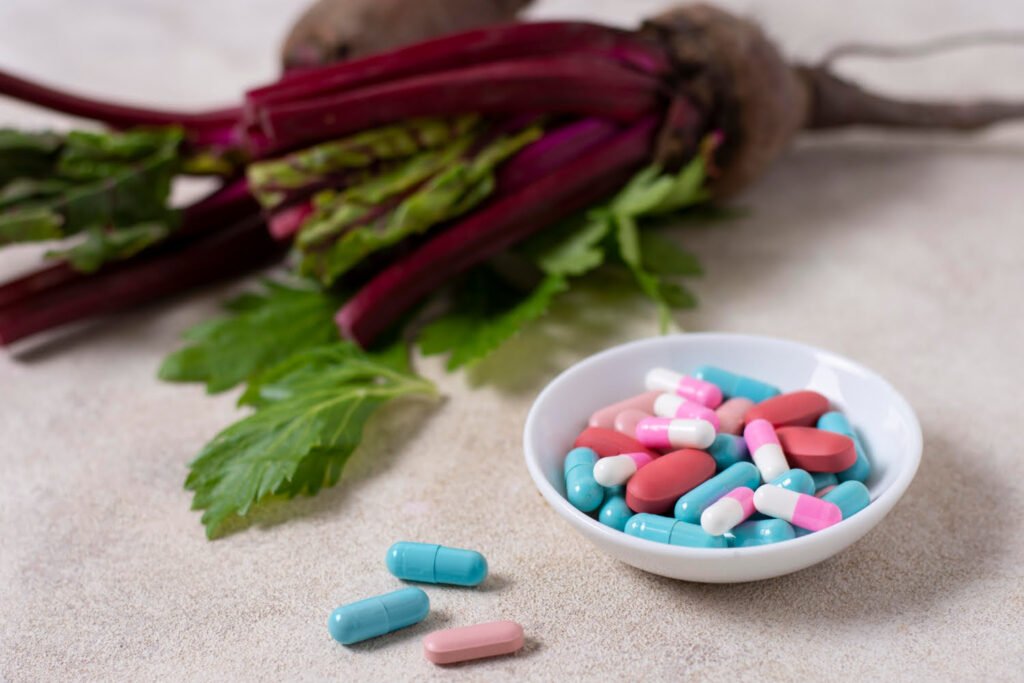 Colourful synthetic capsules contrasted with fresh beetroot and green leaves in the background, illustrating the difference between synthetic and natural supplements.